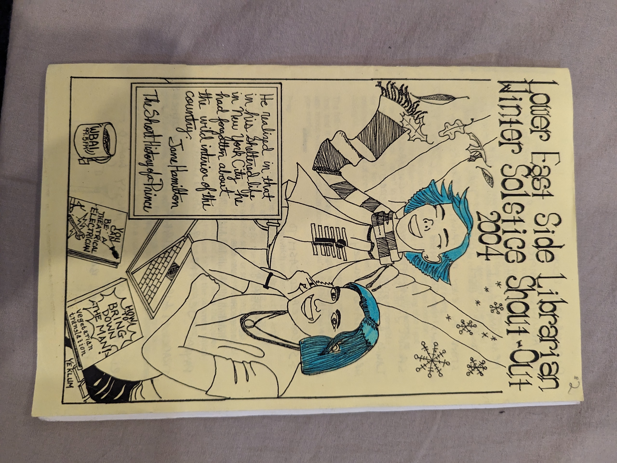 Two ladies with highlighter blue hair enjoying the changing of seasons from fall to winter, and also doing computer work. The cover is a yellow paper.