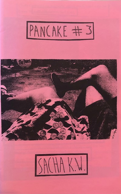 Black ink on pink paper. Grainy image of two pairs of crossed legs.