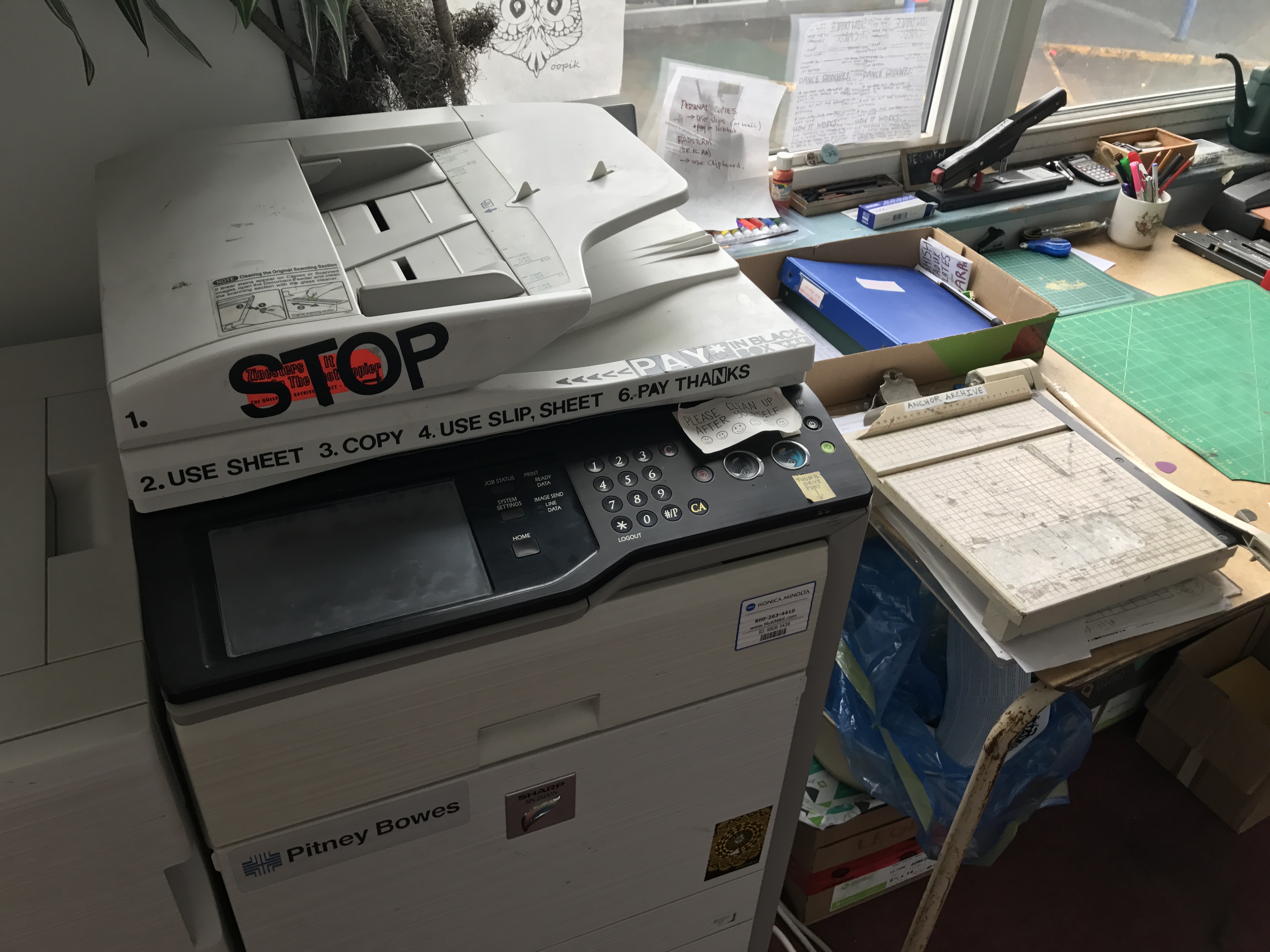 A photocopier sits next to a table with zine-making supplies. 