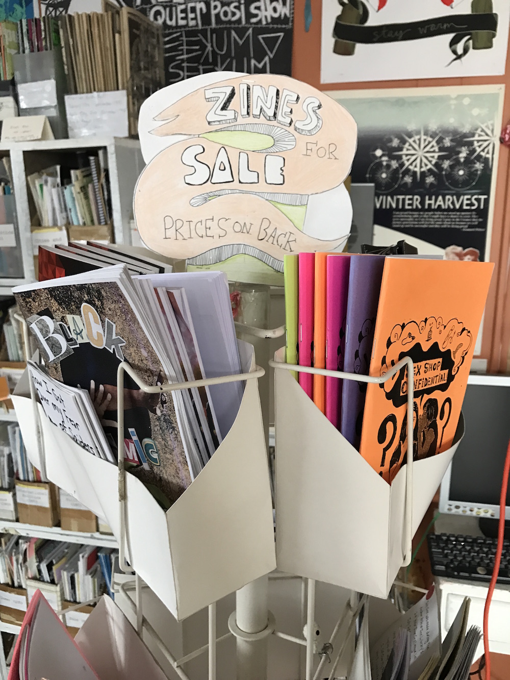 A rack displaying zines reads "Zines For Sale"